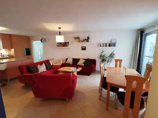 Inviting lounge with plush red sofas, a large coffee table, and an open-plan dining area in the background